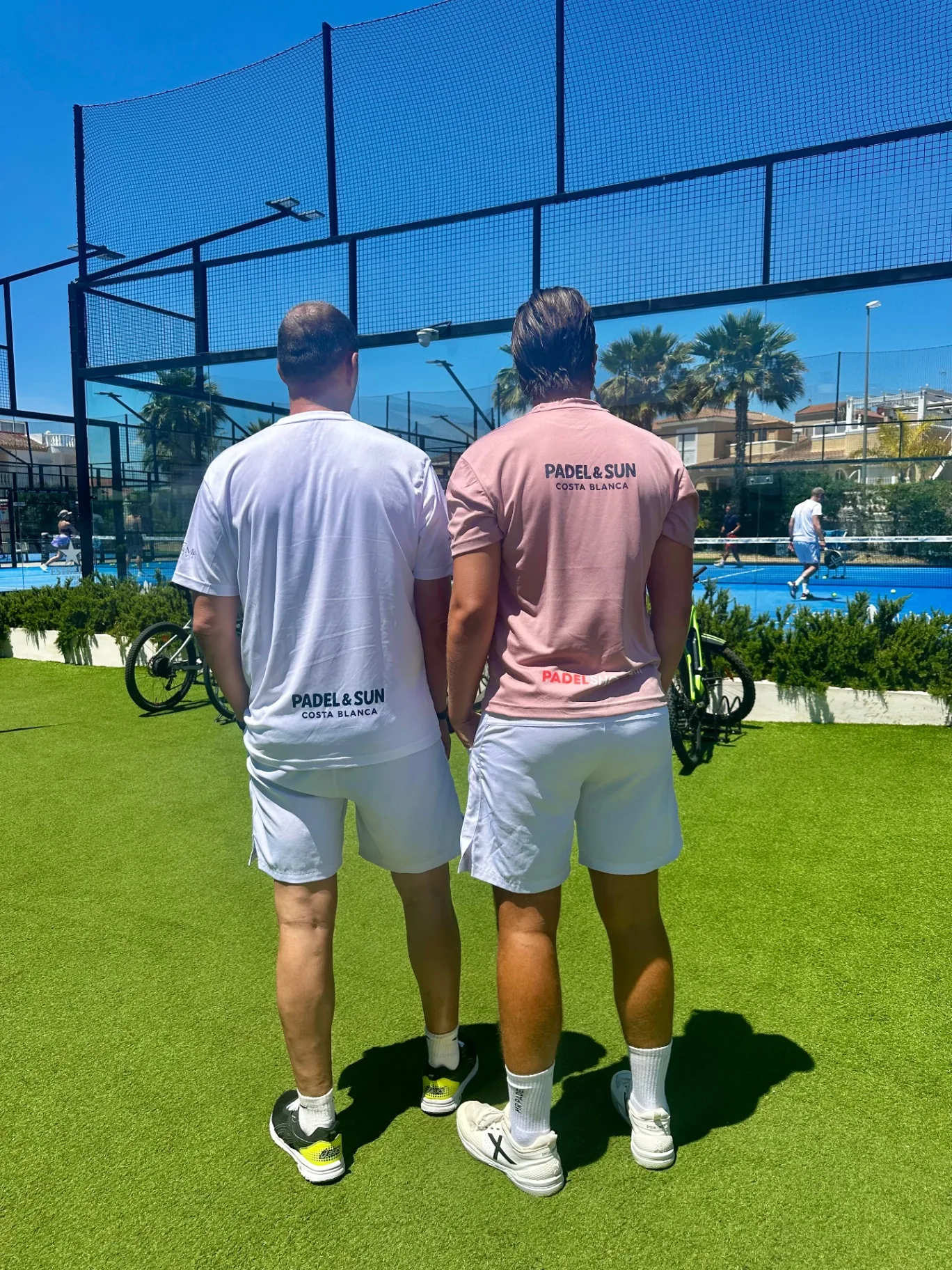Twee deelnemers in Padel & Sun Costa Blanca shirts bij de padelbaan