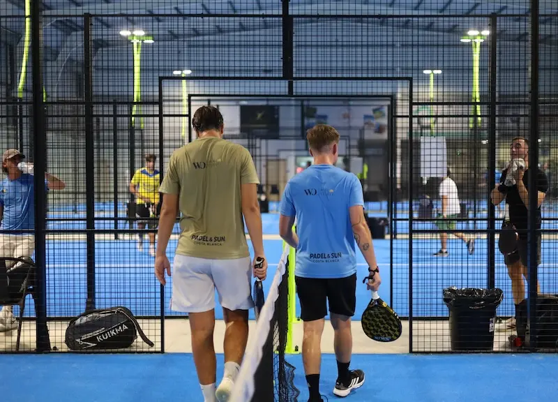 Twee spelers in Padel & Sun Costa Blanca shirts lopen de indoor padelbaan op
